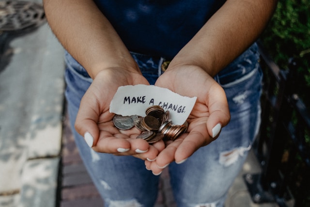 Hands holding coins and a note reading Make a change